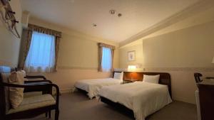 a hotel room with two beds and a chair at Ueno Terminal Hotel in Tokyo