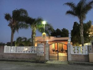 um portão para uma casa com palmeiras à noite em Punta Prosciutto Angel Bay B&B em Punta Prosciutto