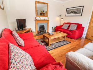 a living room with red couches and a fireplace at Rowantree in Killarney