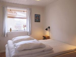 a bedroom with a bed with white sheets and a window at Holiday home Jægerspris XLI in Jægerspris