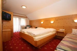 ein Hotelzimmer mit einem großen Bett und einem TV in der Unterkunft Haus Meissnitzer in Haus im Ennstal