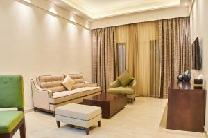 Carlton Dubai Creek Hotel في دبي: غرفة معيشة مع كراسي وأريكة وطاولة