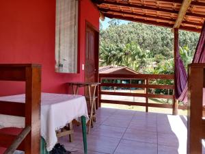 ein rotes Zimmer mit einem Tisch und einem Balkon in der Unterkunft Loft da Serra e Kitnet na Serra in Nova Friburgo