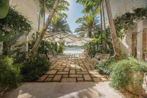 a stone walkway with an umbrella and a pool at Unique lake-front 10-bedroom mansion in most luxurious resort of the caribbean in Punta Cana