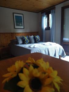 a bedroom with a bed and a table with a yellow flower at Pousada Estrela da Serra in Monte Verde