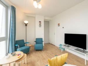 sala de estar con TV de pantalla plana y sillas azules en Sea view apartment in Scherpenisse with terrace, en Scherpenisse