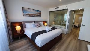 a bedroom with a large bed and a bathroom at OceanView Oasis 2BR Apt - 5Mins to Beach - Family Resort in Gold Coast