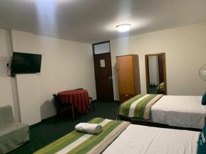 a hotel room with two beds and a television at Hotel Las Mercedes in Trujillo