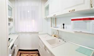 a white kitchen with a sink and a microwave at My Hotel Apartments in Bucharest