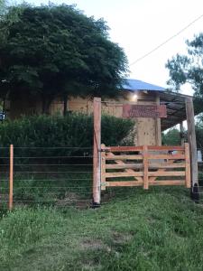 einen Zaun vor einem Gebäude mit einem Schild in der Unterkunft Cabaña Los Nietitos in Tranqueras