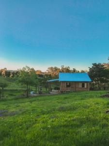 una pequeña casa con techo azul en un campo en Cabaña Los Nietitos, en Tranqueras