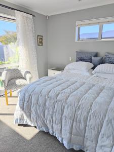 a white bedroom with a large bed and a window at Courtenay B & B in Kaiapoi