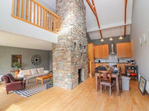 a living room with a stone fireplace and a kitchen at Rosnacarthna More Apartment in Killarney