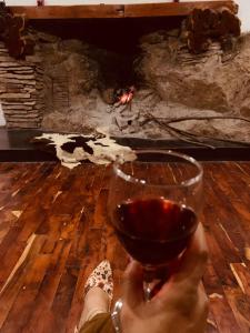 a person holding a glass of wine in front of a fireplace at AYAR - Portentos & Cabañas NIDO DE AYAR in Virú