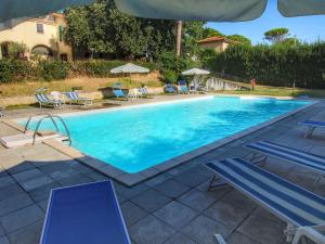 une grande piscine avec des chaises et des parasols bleus dans l'établissement Belvilla by OYO Splendid Farmhouse with Jacuzzi, à Gualdo Cattaneo