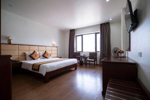 Una habitación de hotel con una cama, un escritorio y una ventana. en LUXURY II HOTEL, en Ha Long
