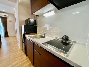 a kitchen with a sink and a black refrigerator at Coral Palace Onna by Sunset Avenue in Onna