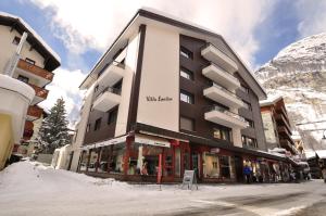 a building in the snow in front of a mountain at La Villa Emeline - Apartment Emilie in Zermatt