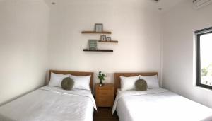 two beds in a room with white walls at K73 De HOUSE in Danang