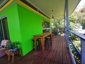 a green wall on a deck with a wooden table at Agutipaca Bungalows in Bagaces