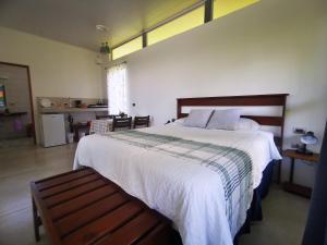 a bedroom with a large white bed with a bench at Agutipaca Bungalows in Bagaces