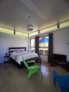 a bedroom with a bed and a green chair at Agutipaca Bungalows in Bagaces