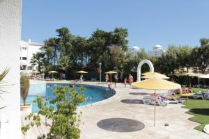 a swimming pool with an umbrella and people sitting around it at Apartment Vila Rosa in Portimão