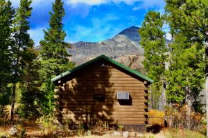 a log cabin with mountains in the background at Summit Mountain Lodge and Steakhouse in East Glacier Park