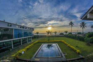 a building with a pool in the middle of a yard at Calypso Sunset in Chilaw