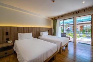 um quarto com 2 camas e uma grande janela em Baan Samui Resort - SHA Extra Plus em Chaweng