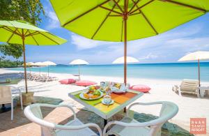 einen Tisch mit einem Teller Essen am Strand in der Unterkunft Baan Samui Resort - SHA Extra Plus in Chaweng