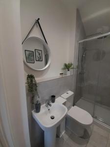 a bathroom with a sink and a toilet and a mirror at The Stables a Contractor Family 2 bed Town House in Central Melton Mowbray in Melton Mowbray