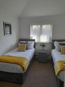 1 dormitorio con 2 camas y ventana en The Stables a Contractor Family 2 bed Town House in Central Melton Mowbray en Melton Mowbray