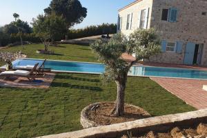 uma árvore num quintal ao lado de uma piscina em Magnificent Stone House Villa 14 beds 7 en-suite rooms Çeşme (450 m2 6500 land) em Cesme