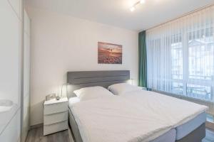 um quarto com uma cama branca e uma janela em Vogelsand 321 em Cuxhaven