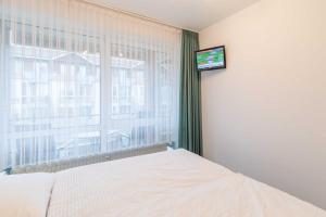 um quarto com uma cama e uma janela com uma televisão em Vogelsand 321 em Cuxhaven
