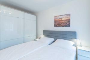 クックスハーフェンにあるVogelsand 321の白いベッド2台が備わるベッドルーム1室、壁に絵画が飾られています。