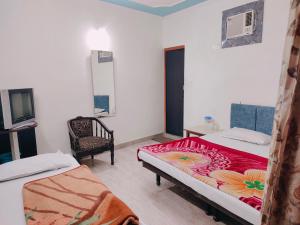a room with two beds and a chair in it at Vidya Guest House in Katra