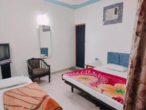 a room with two beds and a chair in it at Vidya Guest House in Katra