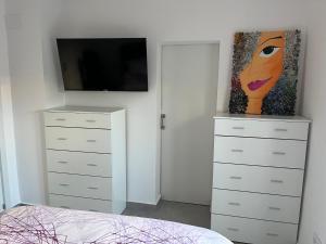 - une chambre avec une commode, une télévision et un tableau dans l'établissement Adosado de lujo en Olivanova Golf con 3 dormitorios, à Oliva
