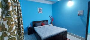 a bedroom with a bed and a blue wall at Miltonia Bliss Homestay in Siliguri