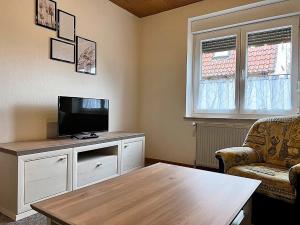 een woonkamer met een tv en een bank en een tafel bij Haus Waldluft Whg. Birke in Cuxhaven