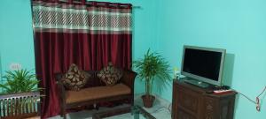 salon z czerwoną zasłoną i telewizorem w obiekcie Miltonia Bliss Homestay w mieście Siliguri