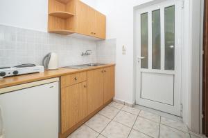 een keuken met houten kasten, een wastafel en een deur bij ALADDIN TSILLIVi in Tsilivi