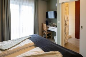 a bedroom with a bed and a desk with a television at Stadthotel Jever in Jever