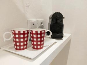 Deux tasses à café rouges et blanches assises sur une étagère dans l'établissement Via Poma Rooms, à Vérone