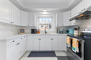 a white kitchen with white cabinets and a window at Casa Soleada in East Rock near DT and Yale SOM with FREE Parking and King Bed in New Haven