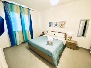 sypialnia z łóżkiem z niebieskim kocem i zasłonami w obiekcie Luisa Home w mieście Porto Torres