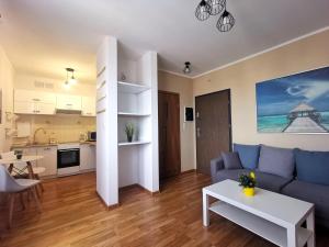 a living room with a blue couch and a table at Euro24 Apartamenty Rumia Klon - studio z balkonem in Rumia