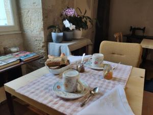 a table with two cups and a plate of food at Le rêve d'Alice in Saint-Puy